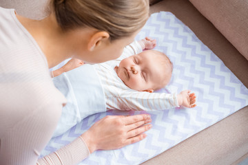 high angle view of young mother looking at adorable infant baby lying on sofa