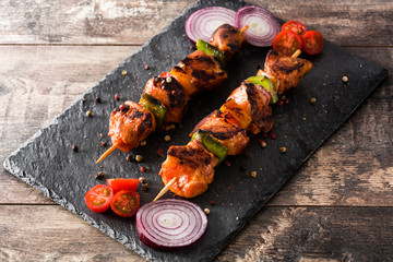 Chicken shish kebab with vegetables on wooden table