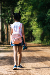 Asian little girl with camera traveling alone in tropical forest.
