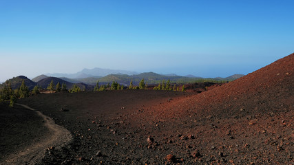 Path through the lunar landscape of Montaña Samara in Teide National Park, one of the most alien-like, volcanic land in Tenerife with views towards the western coast of the island