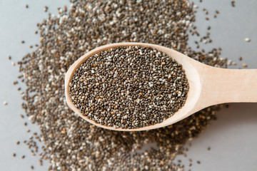 Chia seeds in wooden spoon on grey background.copy spase.Chia seeds in wooden spoon, lying on dark stone background