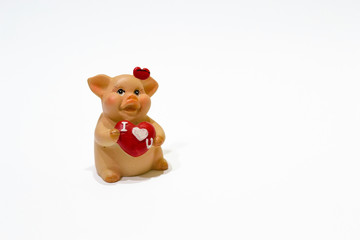 I love you. Closeup ceramic toy pig with red heart isolated on white background. Happy Valentine's Day and China NEw 2019 Year. Symbol of the year. Copy space.