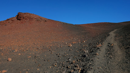 Path through the lunar landscape of Montaña Samara in Teide National Park, one of the most alien-like, volcanic land in Tenerife with views towards Pico del Teide, Pico Viejo, and Las Cuevas Negras