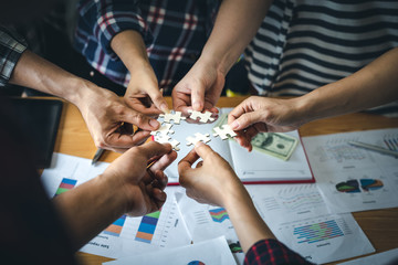 Business people hold paper jigzaw puzzle