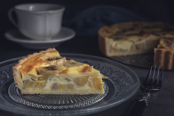 Sliced homemade banana custard tart served in a plate. Horizontal, closeup