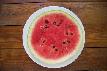 Pieces of watermelon in bowl and slice on white plate. Top view