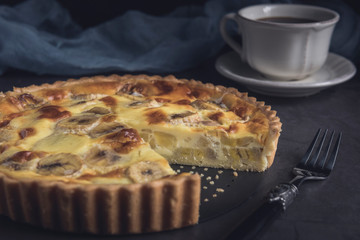 Sliced homemade banana custard tart with cup of coffee. Horizontal