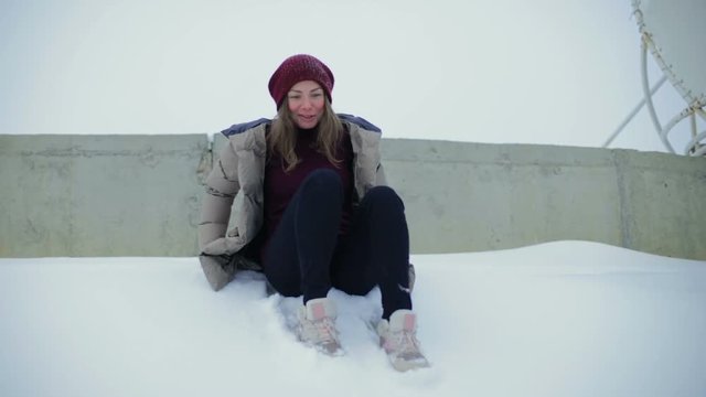 slow motion pretty girl slides down from hump and screams admiringly in winter under endless overcast sky