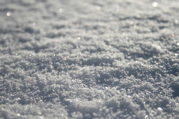 Snow surface close up, winter background with snowflakes at sunset