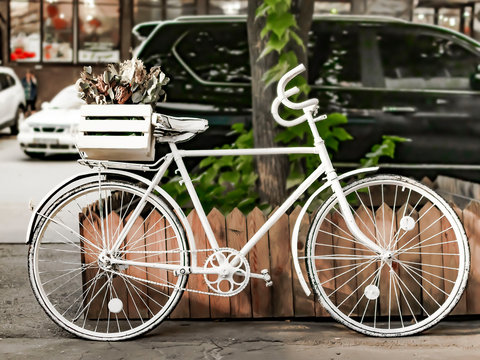 Painted white bike on street of European city near road with cars