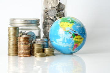 Global economy concept with sphere globe and stacked of coins over white.