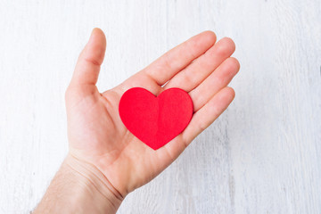 Fototapeta premium Heart shaped paper in opened palm on whit background showing love and hope.