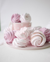Pink and white meringues on white background