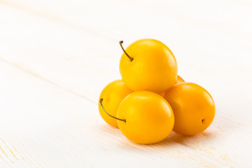 Yellow cherry plums on white wooden surface