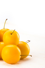 Yellow cherry plums on white wooden surface