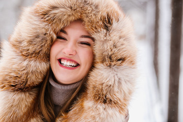 Beautiful girl in fur on a winter background posing on camera, enjoying life, laughing, beautiful...