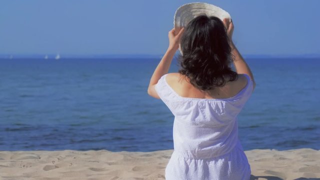 Woman in hat relaxing on ocean shore