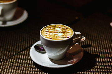 A cup of coffee in the dark on a wooden table with a foam pattern