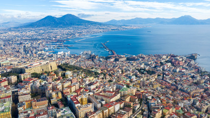 Fototapeta na wymiar Aerial view of Naples from the Vomero district. You can see Castel Sant'elmo in the foreground while in the background the city's port, the Vesuvius and the Ovo castle. There are houses and buildings.