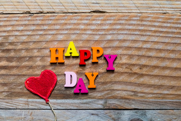 Happy day écrit en lettres bois et coeur rouge sur un fond bois