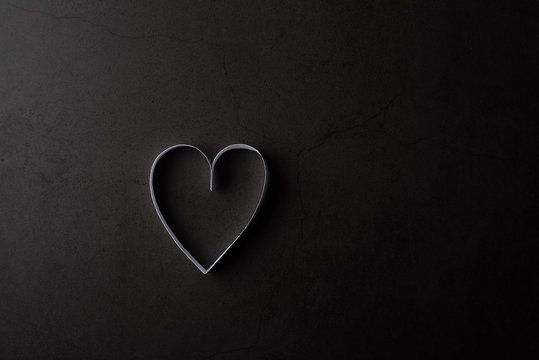 White heart shaped paper in shadow on black background