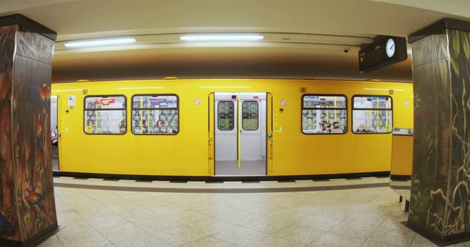 Yellow train in subway station with people inside, open door. Big city, stop, electric, metal, metro, railway system, traffic, urban, technology.