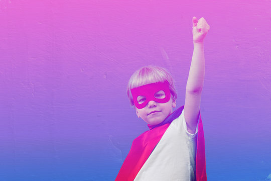 Cute boy in superhero costume on purple duotone background