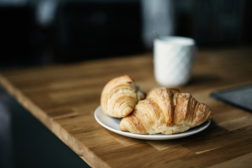 Croissant and cup of coffee on wooden table