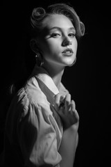 Black and white portrait of young pretty girl in retro style in drematic light with noise add.