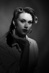 Black and white portrait of young pretty girl in retro style in drematic light with noise add.