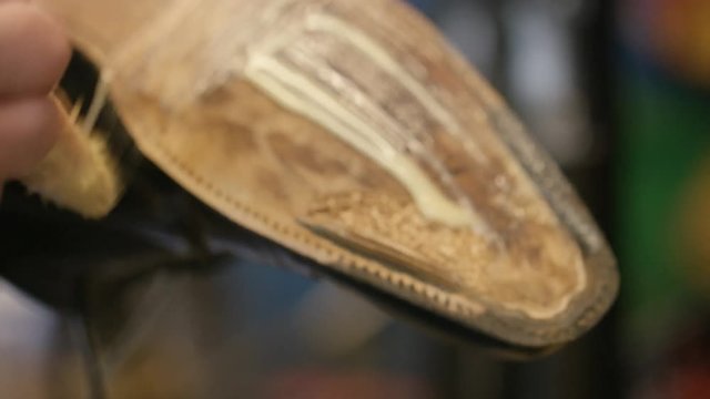 Cobbler applying glue to the sole of a leather shoe