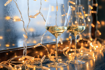 Closeup of two glasses of white wine in transparent crystal glasses on background of window and...