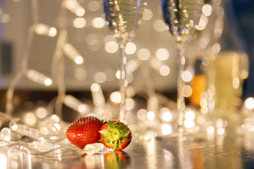 Closeup strawberry, two crystal glasses, bottle champagne sparkling wine, reserved nameplate on wooden table, window, garlands. Concept date evening in restaraunt, 8 march, Valentine's Day, christmas