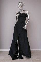 Fototapeta na wymiar Black designer, evening, women's dress handmade on gray, glossy mannequin isolated on gray background