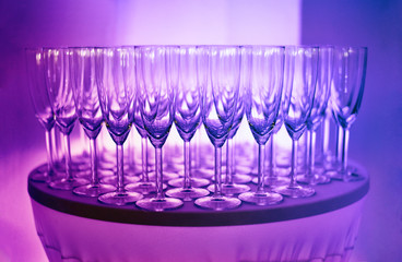 Close up of empty prosecco glasses for welcome drink. Purple and pink party light.