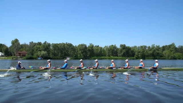 Rowing team summer training. 8 athletes rowers in a boat in the river Dnipro. City area in Kiev, Ukraine