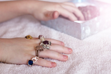 Children's hand and a lot of beautiful rings, jewelry