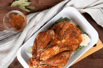Raw guinea fowl smeared with spices with paprika lies on a white dish for baking with garlic and rosemary