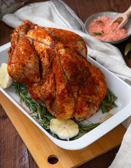 Raw guinea fowl smeared with spices with paprika lies on a white dish for baking with garlic and rosemary