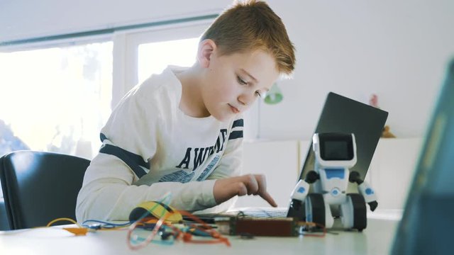 Kid plays with computer and electronics and start to type on the keyboard