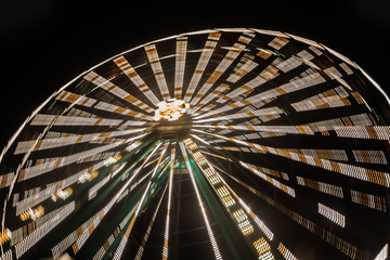 Ferris wheel in motion at the amusement park, night illumination. Long exposure