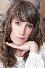 Curly long haired Caucasian woman portrait with head reclined upon her hand