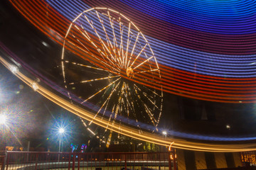 Ferris wheel in motion at the amusement park, night illumination. Long exposure