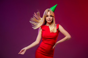 Event, party, Birthday, Christmas or New Year celebrating concept . Having fun. Young pretty blond woman in red dress and birthday hat is laughing. Studio portrait with bright background. Copy space