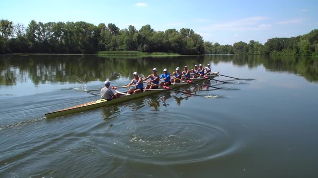 Rowing team summer training. 8 athletes rowers in a boat in the river Dnipro. City area in Kiev, Ukraine