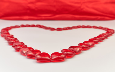 Obraz premium Heart shaped lined from small glass red hearts on a white and red background. Valentine's Day. Love symbol copy space