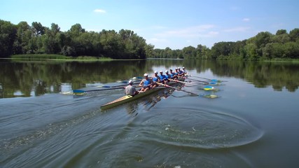 Rowing team summer training. 8 athletes rowers in a boat in the river Dnipro. City area in Kiev, Ukraine