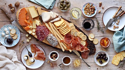Naklejka na ściany i meble Appetizers table with various of cheese, curred meat, sausage, olives and nuts Festive family or party snack concept. Overhead view.
