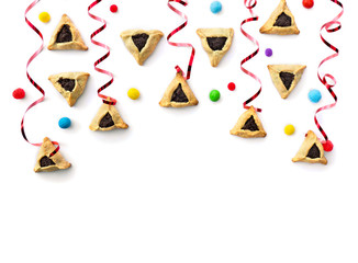 Triangular cookies with poppy seeds (hamantasch or aman ears ), colored candy and red serpentine for jewish holiday of purim celebration on white background with space for text. Top view, flat lay