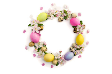 Easter decoration. Circle Easter frame of pink flowers apple tree, colored easter eggs and quail eggs on white background with space for text. Top view, flat lay